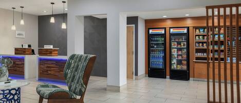 A reception area with a counter, a chair, and a refrigerator stocked with beverages.