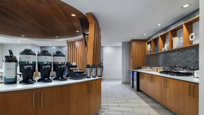 A modern kitchen with wooden cabinets, a curved countertop, and a built-in stove. - SpringHill Suites Dallas Arlington North (Arlington)