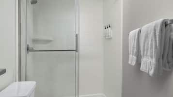 Un baño moderno con ducha de vidrio, azulejos blancos y un perchero con toallas.