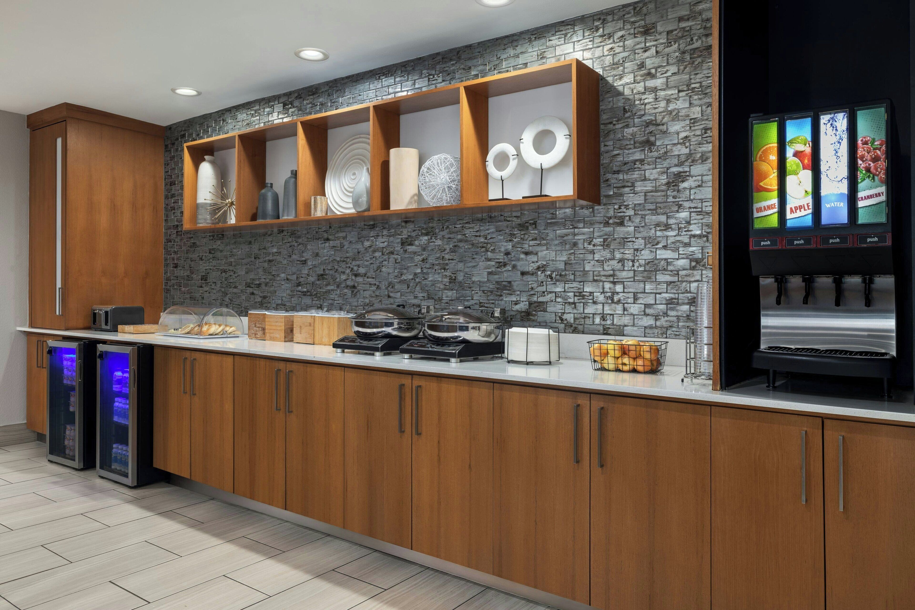 Una cocina moderna con armarios de madera, salpicadero de ladrillo y dispensador de bebidas.
