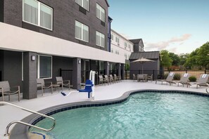 A modern building with a pool, outdoor seating, and a covered area. - SpringHill Suites Dallas Arlington North (Arlington)