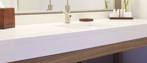A modern bathroom with a white vanity, a large mirror, and a framed artwork.