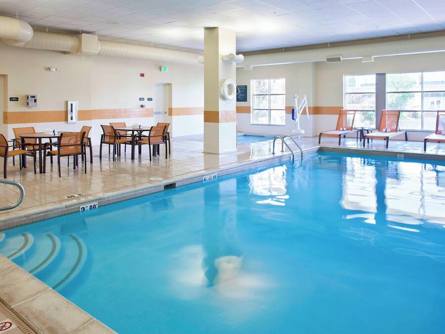 A swimming pool with lounge chairs and a dining area with tables and chairs.