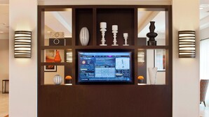 A reception area with a digital display, decorative items, and wall-mounted lighting. - Courtyard by Marriott Pueblo Downtown (Pueblo)