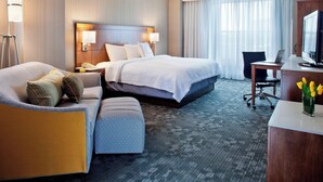 A hotel room with a large bed, a desk with a computer, a chair, and a lamp. - Courtyard by Marriott Pueblo Downtown (Pueblo)