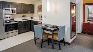 A modern kitchen with dark cabinets, stainless steel appliances, and a dining area with two chairs and a table. - Residence Inn by Marriott Portsmouth (Portsmouth)