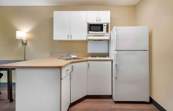 A compact kitchen with white cabinets, a microwave, a refrigerator, a sink, and a countertop. - Extended Stay America Suites Philadelphia Cherry Hill (Cherry Hill)