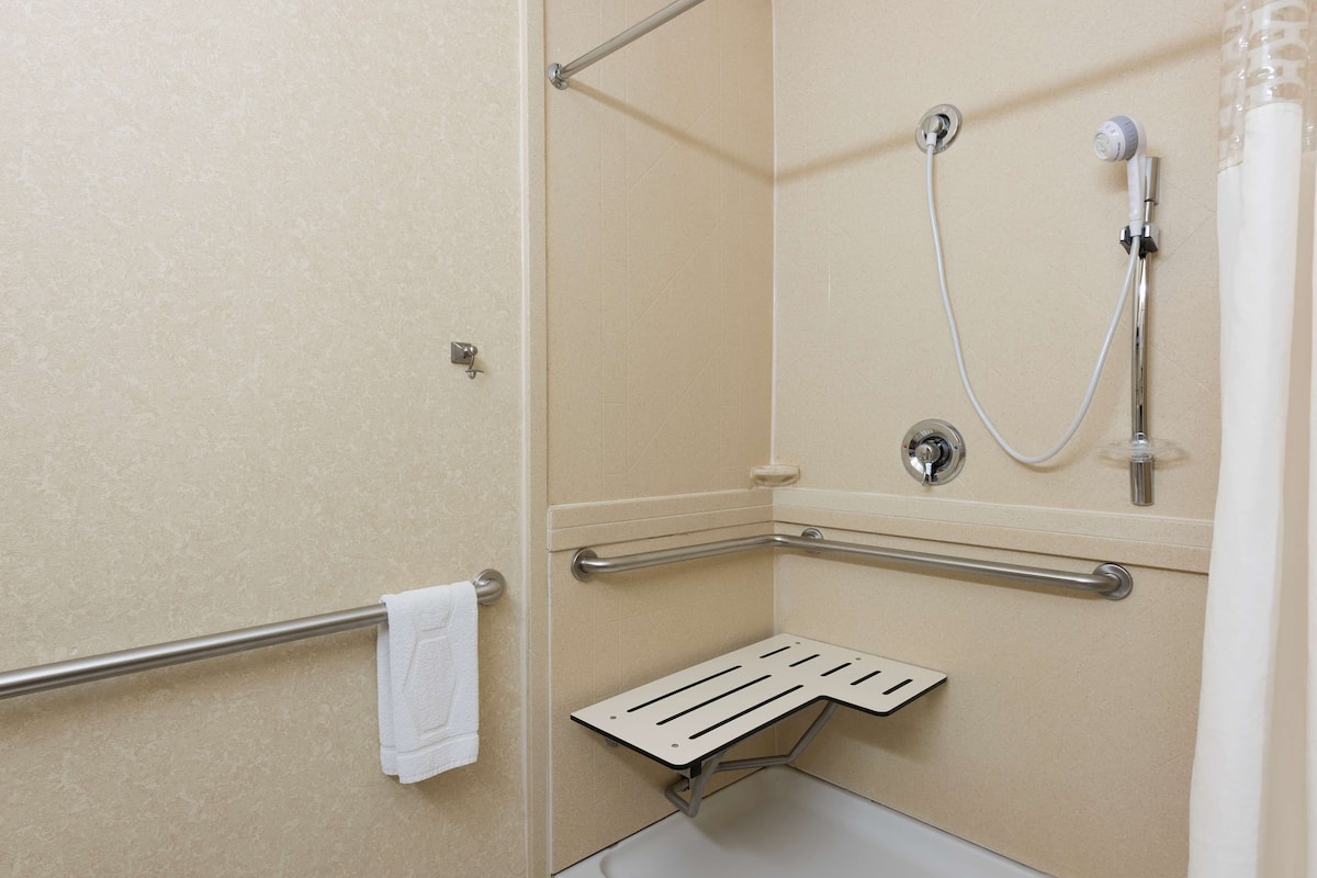 A shower area with a grab bar, a towel rack, and a showerhead.