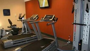 A gym with treadmills, a TV, and a weight machine.