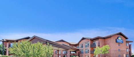 A Days Inn & Suites building with a brick facade, multiple balconies, and a clear blue sky.