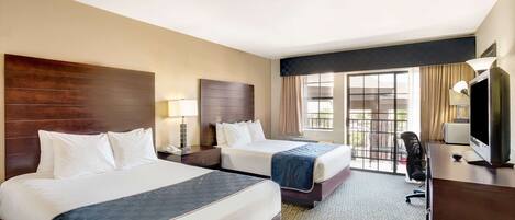 A hotel room with two beds, a desk, a TV, and a window with curtains.