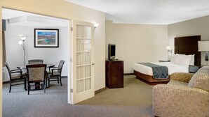 A hotel room with a bed, a TV on a stand, a desk with a chair, and a dining area with chairs. - Days Inn & Suites by Wyndham Page Lake Powell (Page)