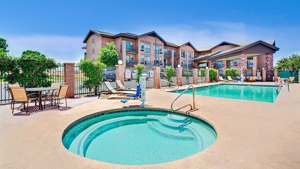 A hotel with a swimming pool, outdoor seating, and a brick facade. - Days Inn & Suites by Wyndham Page Lake Powell (Page)