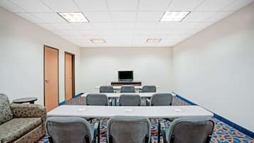 A conference room with a long table, six chairs, a laptop on a stand, and a sofa.