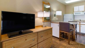 A compact hotel room with a flat-screen TV, wooden dresser, a dining area with a table and chairs, a microwave, and a refrigerator. - Extended Stay America Select Suites Baltimore BWI Airport (Linthicum Heights)