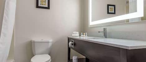 A bathroom with a toilet, a sink with a mirror, and a shower curtain.