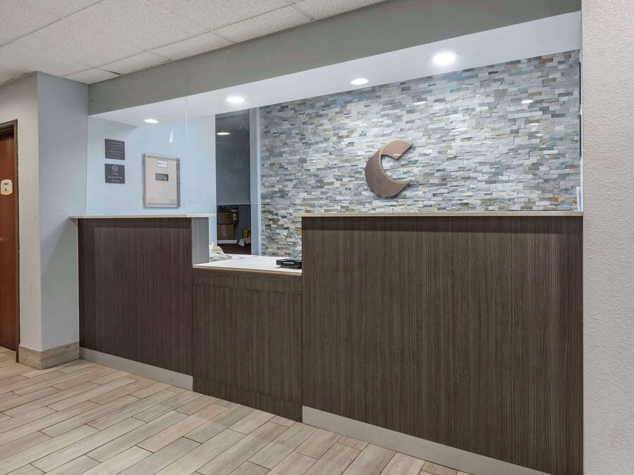 Zona de recepción con un mostrador de madera, un reloj en la pared y una gran decoración en forma de luna creciente.