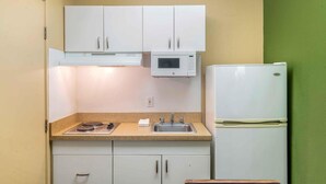 A compact kitchen with white cabinets, a microwave, a sink, and a refrigerator. - Extended Stay America Suites Portland Beaverton (Beaverton)