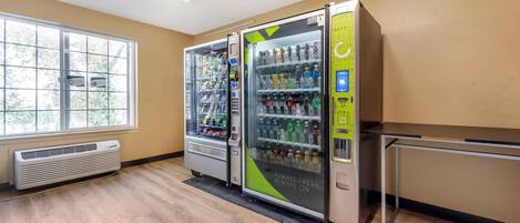 A room with two vending machines, a window, a radiator, and a table.