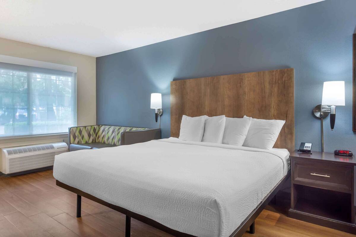 Habitación de hotel con una cama grande, dos lámparas de noche, una mesita de noche y una ventana con vistas a árboles.