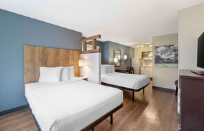 Une chambre d’hôtel avec deux lits, une tête de lit en bois, un bureau et une chaise.