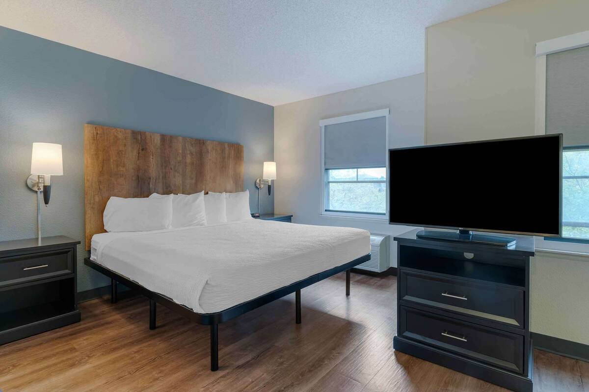 Habitación de hotel moderna con una cama grande, televisión de pantalla plana, escritorio con silla y ventana con vistas.