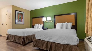 Habitación de hotel con dos camas, paredes verdes y un cuadro enmarcado en la pared.