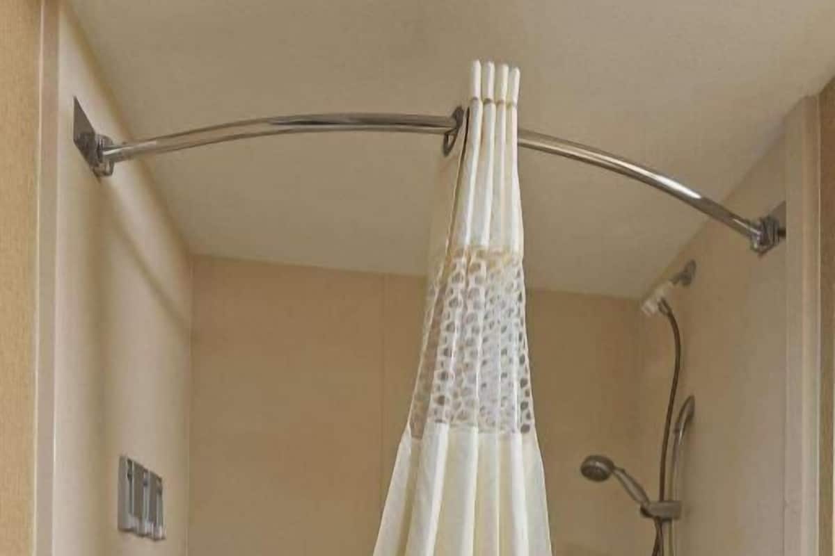 A bathtub with a shower curtain, grab bars, and a towel.