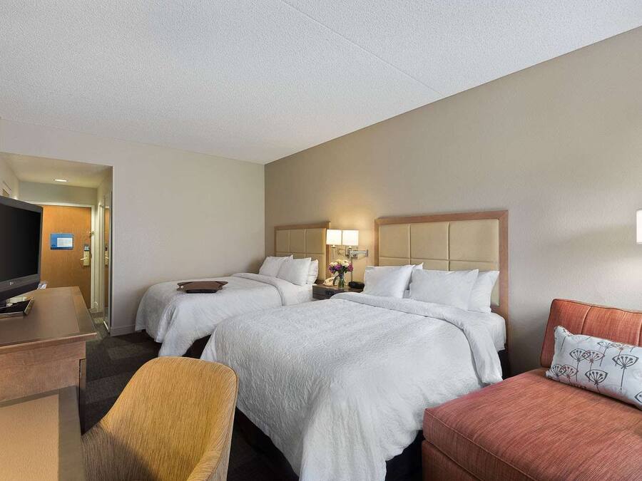 Une chambre d’hôtel avec deux lits, une télévision, un bureau et une chaise.