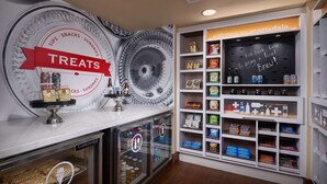 Exposição de doces numa pastelaria, com um letreiro que diz "TREATS" e prateleiras repletas de produtos de pastelaria e snacks.