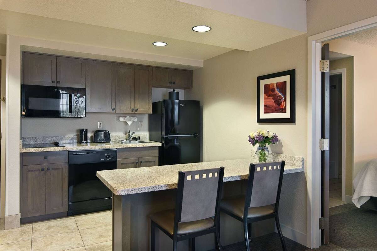 Cocina compacta con microondas, refrigerador, pileta y comedor para dos personas.
