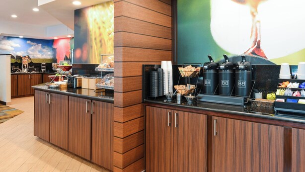 A hotel reception area with wooden cabinets, a coffee station, and a mural on the wall.