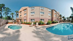 A hotel with a pool area, including two pools and lounge chairs.
