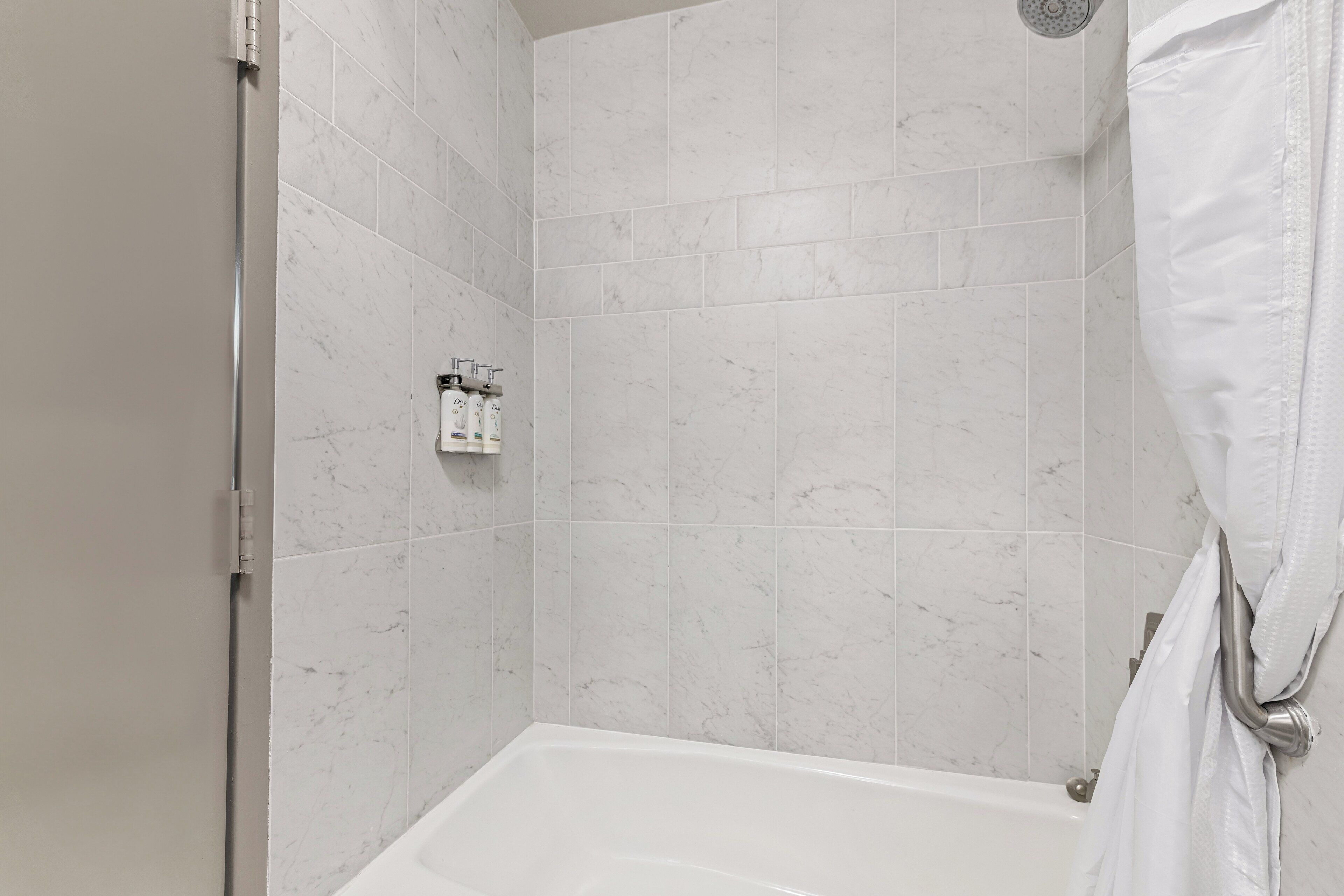 A modern bathroom with a shower, white tiles, and a bathtub.