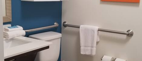 A bathroom with a toilet, a sink, a towel rack, and a framed picture on the wall.