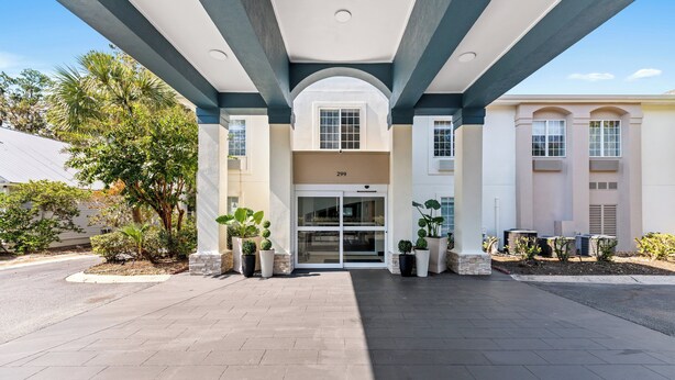 A building entrance with a covered walkway, potted plants, and a clear sky. - Holiday Inn Express Saint Simons Island by IHG (St. Simons Island)