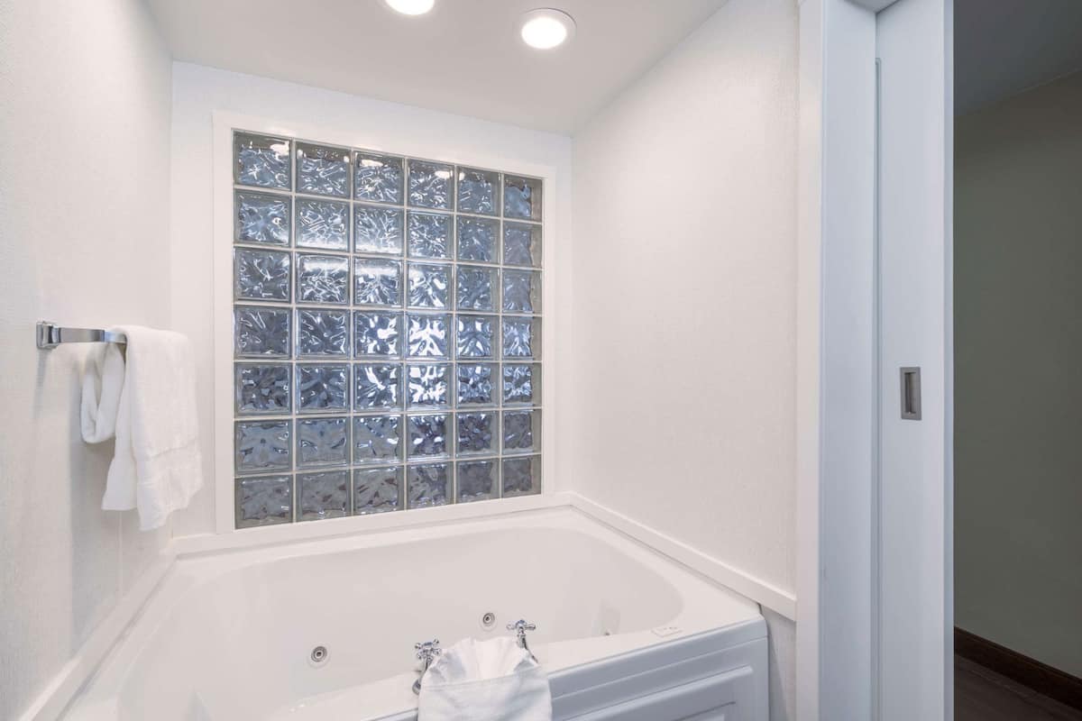 Une salle de bain avec une baignoire, une fenêtre à vitre dépolie et un porte-serviettes.