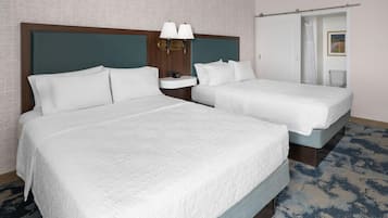 Une chambre d’hôtel avec deux lits, une table de chevet, une lampe et une porte de salle de bain.