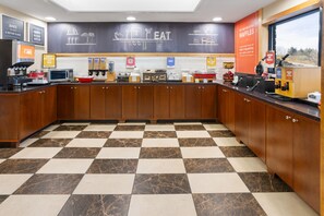 A breakfast bar with a checkered floor, kitchen appliances, and a chalkboard menu. - Hampton Inn Frostburg (Frostburg)