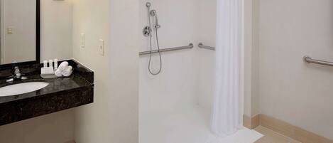 Un baño moderno con lavamanos, espejo y ducha.