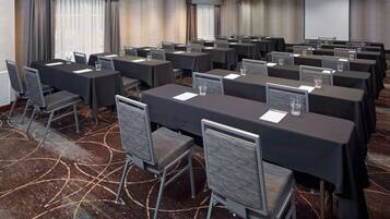 A conference room with multiple tables and chairs, arranged in rows.