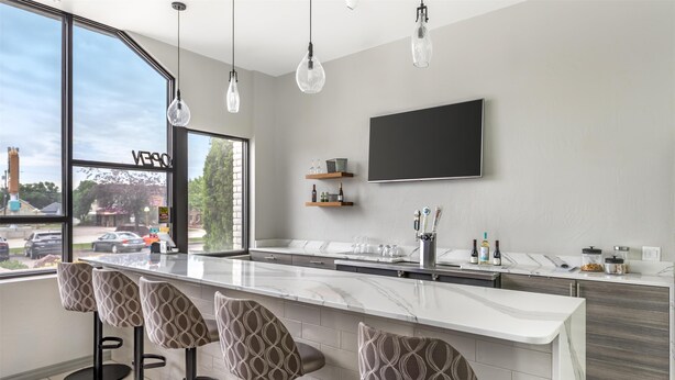 Une cuisine moderne dotée d’un grand îlot central, de tabourets de bar, de luminaires suspendus et d’une grande fenêtre offrant une vue sur l’extérieur.