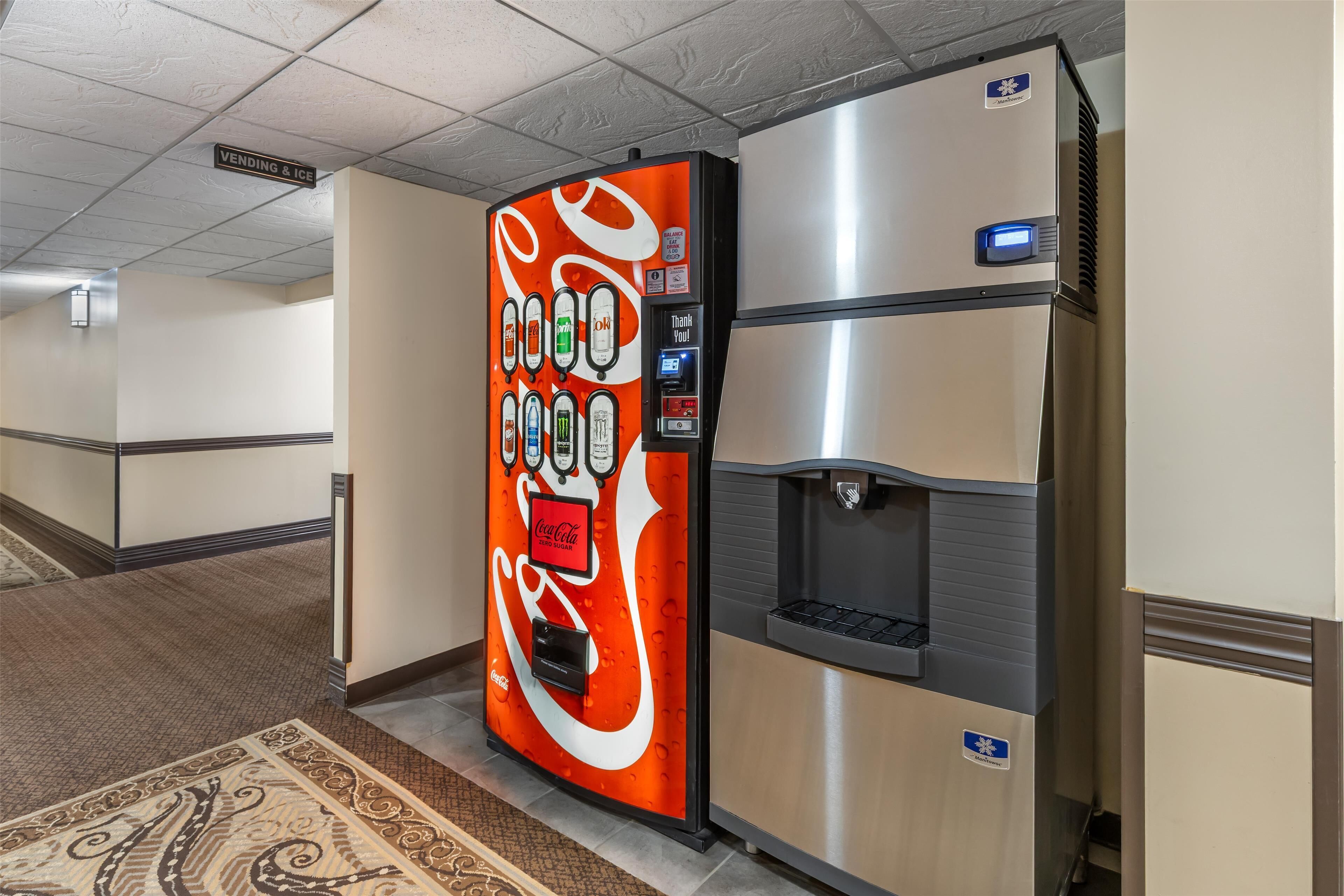Una máquina expendedora con el logotipo de Coca-Cola, un dispensador de agua y una pantalla digital.