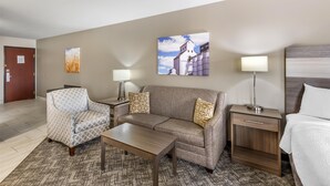 Une chambre d’hôtel comprenant un canapé, un fauteuil, des tables de chevet, des lampes et un lit.