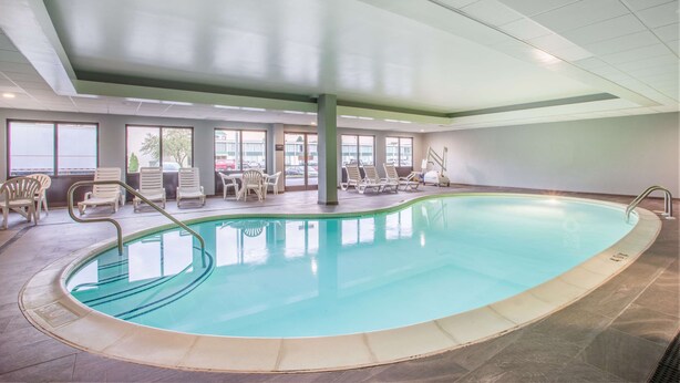 An indoor swimming pool with clear water, surrounded by lounge chairs and a tiled floor.