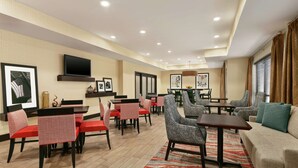 Eine Hotelhalle mit Essbereich, Sofas und einem an der Wand befestigten Fernseher.