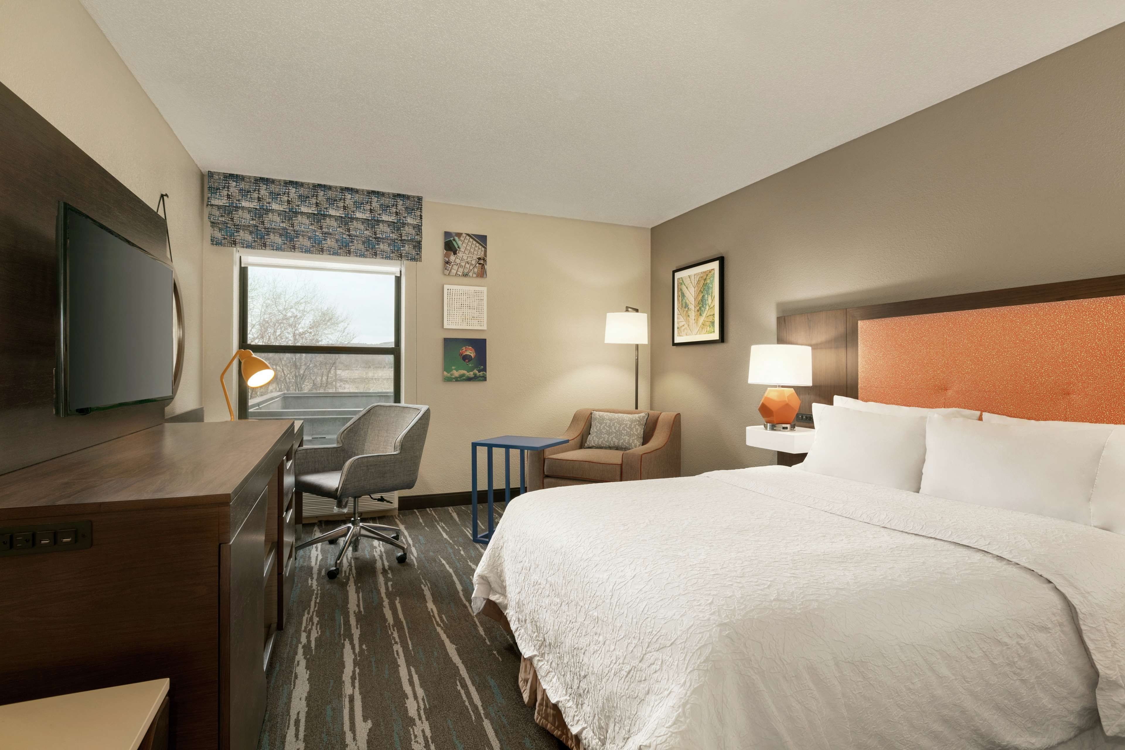 Una habitación de hotel con cama, escritorio, silla y televisión.