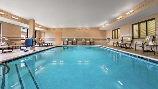 Ein Schwimmbecken mit mehreren Bahnen, Liegestühlen und einer Tür zu einem weiteren Raum.