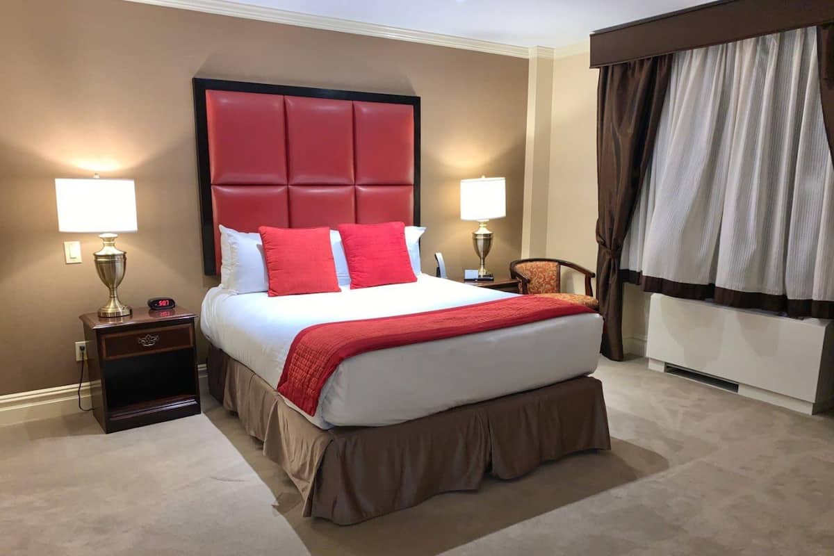 Quarto de hotel com uma cama grande, duas mesinhas de cabeceira e uma cabeceira.