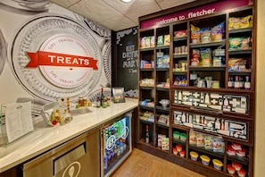 A snack and treat section with a variety of packaged goods and a menu board. - Hampton Inn & Suites Asheville Airport (Fletcher)